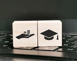 Stock image of block with hand and graduation cap on a laptop